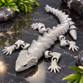 Silver articulated lizard fidget toy on black marble