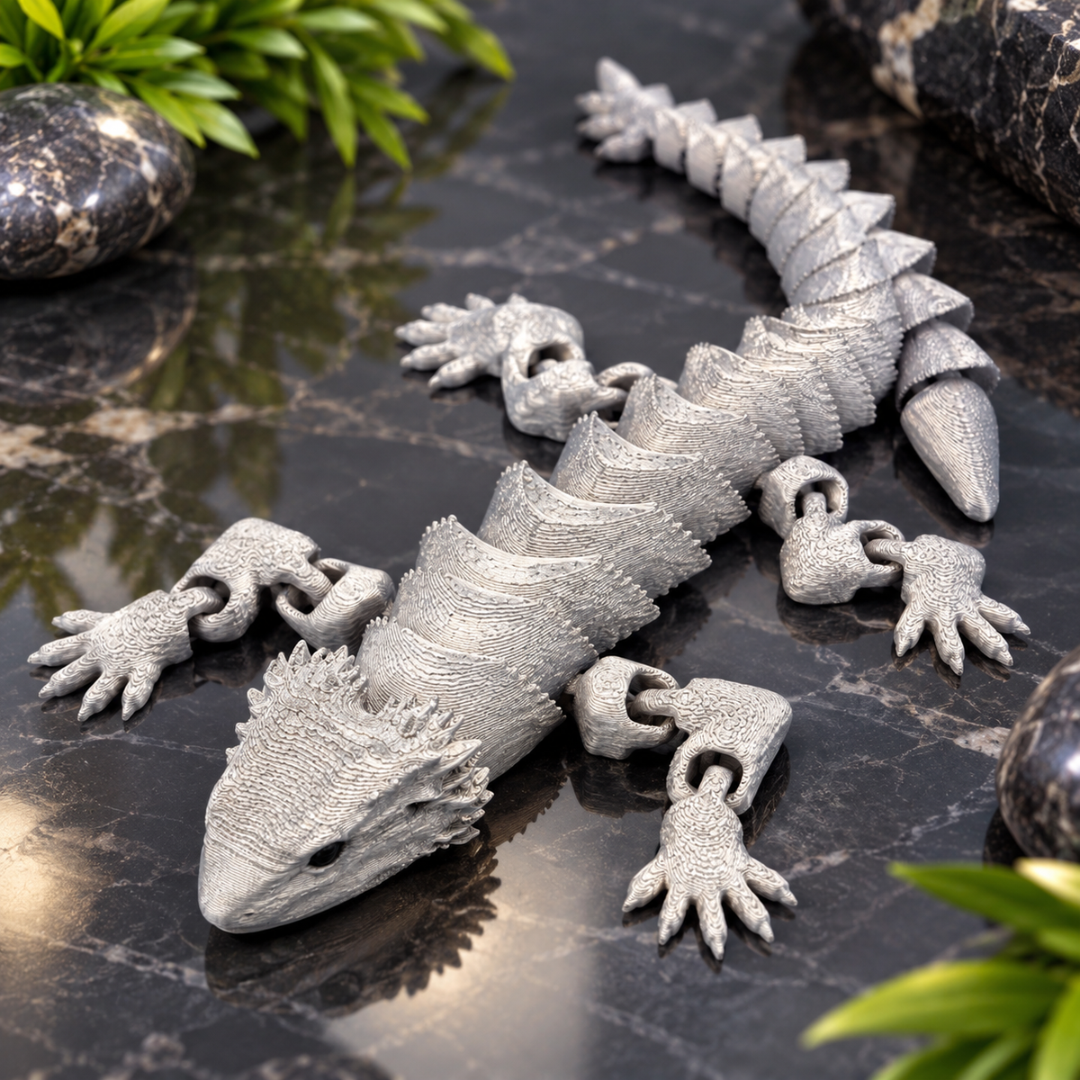 Silver articulated lizard fidget toy on black marble